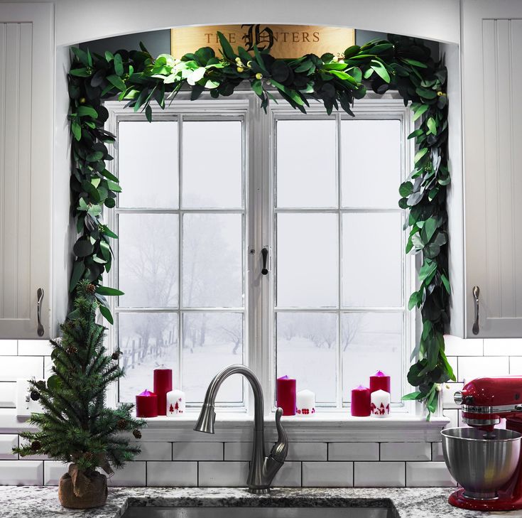 a kitchen sink sitting under a window covered in greenery