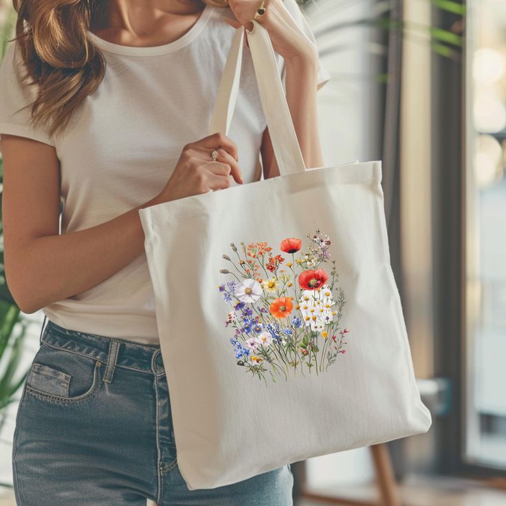 This Cotton Canvas Tote Bag features a beautiful Wildflower bouquet in an wildflower design, giving off a charming and natural vibe. Perfect for nature lovers and those who appreciate floral motifs. Ideal for carrying groceries, books, or everyday essentials. Great for eco-conscious individuals and makes a lovely gift for Mother's Day or birthdays. This 100% cotton bag comes in one size - 15" x 16"- perfect for everyday wear. While the canvas material will show off your designs in great colors, it's durable and will last for years. The bag features 20" handles (made from the same canvas), making it easy to carry even with a week's worth of shopping. .: 100% cotton canvas .: Heavy fabric (12 oz/yd² (406.9 g/m .: Sewn-in label .: Available in natural and black colors White Botanical Bag For Daily Use, White Botanical Bags For Daily Use, White Floral Print Flower-shaped Shoulder Bag, White Floral Print Flower Shaped Shoulder Bag, White Botanical Bags For Everyday, White Botanical Style Bags For Everyday, White Canvas Bag Spring Gift, White Canvas Bag For Spring Gift, White Botanical Tote Bag