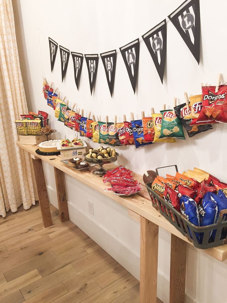 an assortment of snacks are displayed on a long table with bunting and pennants