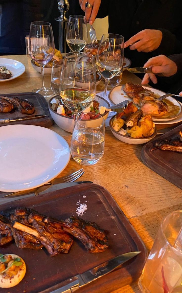 people sitting at a table with food and wine glasses on top of the plates in front of them