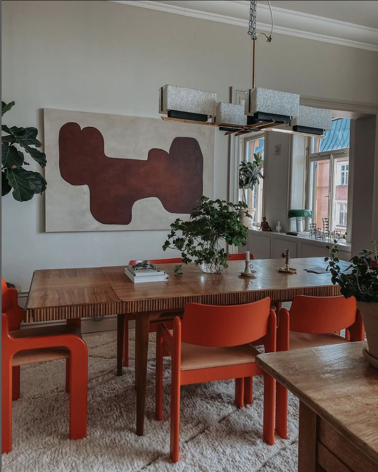 a dining room table with orange chairs around it