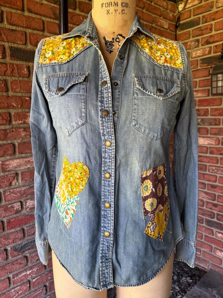 a denim shirt with patches and flowers on the front, sitting on a mannequin's head