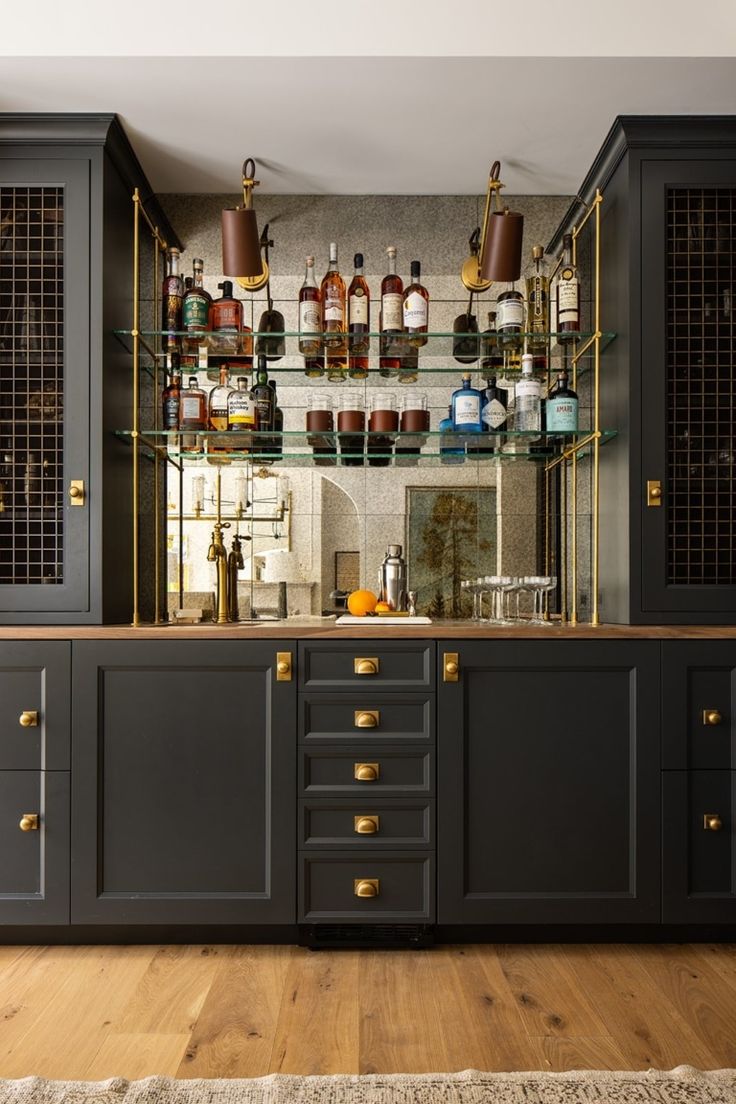 a kitchen with lots of bottles on the wall and shelves above it, along with wooden flooring