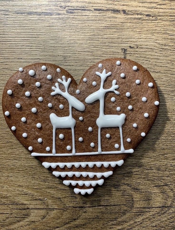 a heart shaped gingerbread with white frosting and reindeer on it's side