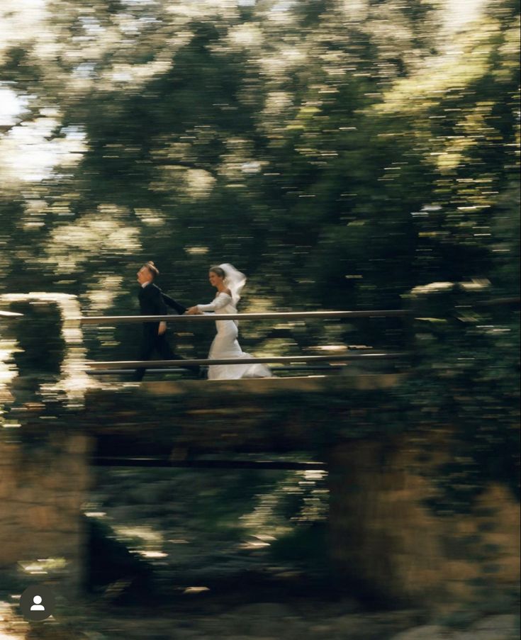 a bride and groom walking across a bridge