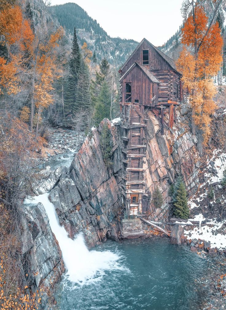 an old water mill on the side of a mountain