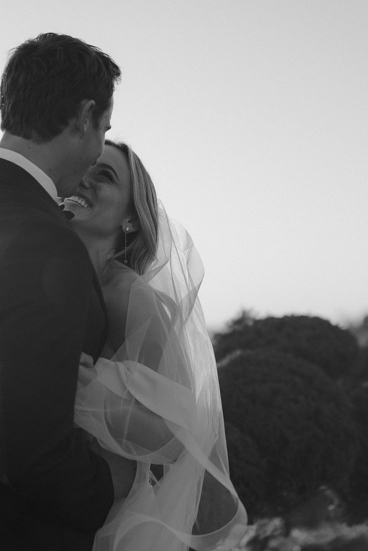 a bride and groom kissing in front of the ocean