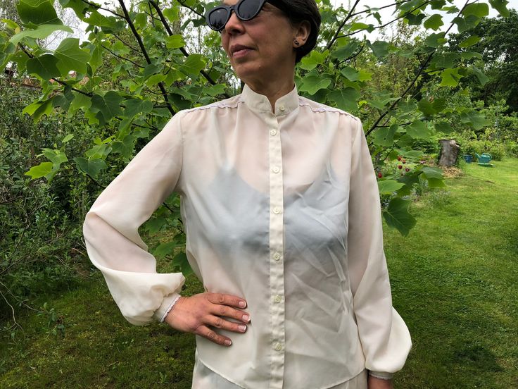 Vintage 80s egg shell colour blouse with stand up collar. Puff sleeve blouse with eyelet lace details on shoulders. Vintage front buttoned blouse. Marked as size 40. Made in West Germany. From shoulder to shoulder  15" 38cm Bust  40"  102cm Sleeve length  23"  58cm Length  23" 58cm. Fitted Summer Blouse With Stand Collar, Fitted Stand Collar Blouse For Summer, Spring Stand Collar Blouse For Daywear, Stand Collar Blouse For Spring Daywear, Stand Collar Blouse For Daywear In Spring, Fitted Shirt With Stand Collar For Spring, Spring Office Tops With Stand Collar, Summer Workwear Blouse With Stand Collar, Summer Stand Collar Blouse For Workwear