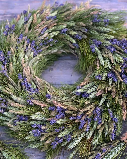 a wreath made out of grass and lavenders on top of a wooden table,