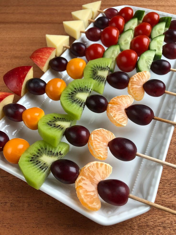 fruit skewers are arranged on a white platter, ready to be eaten