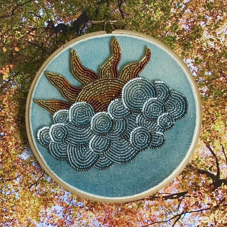 an embroidery project is shown in the shape of a sun and clouds on a blue background