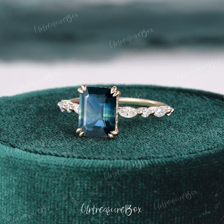 a ring with a blue stone surrounded by white diamonds on top of a green velvet box