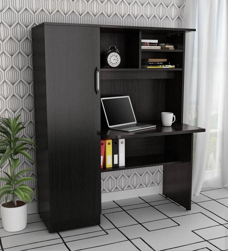 a computer desk with a laptop on top of it next to a potted plant