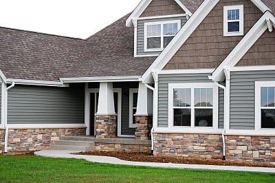 a house with gray siding and white trim on the windows, grass in front of it