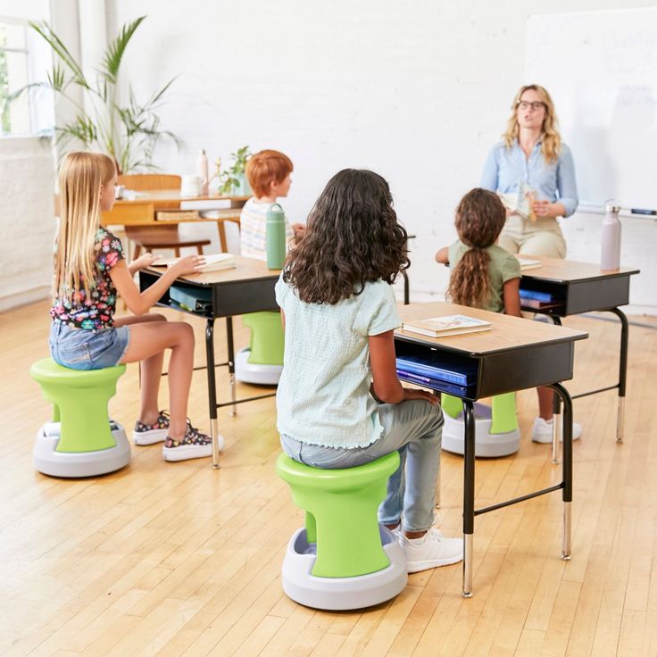 several children sitting at desks in front of a whiteboard