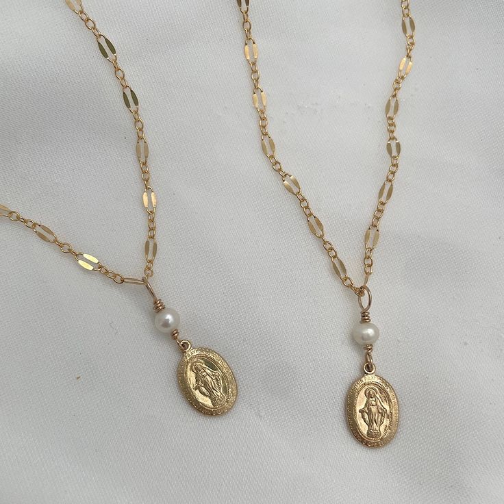 Our Miraculous Medal Dainty Necklace is a beautiful reminder of faith and the power of prayer. This beautiful necklace features a hand-wired accent stone of your choice on a delicately accented chain. 9mm x 13mm Miraculous Medal charm in sterling silver or 14kt gold fill hand-wired pearl or pyrite charm accent sterling silver or 14kt gold fill chain for long-term worry-free wear Our handmade pieces are made with care, orders ship within 5 to 10 business days Miraculous Medal Necklace, Shell Charm Necklace, Initial Charm Bracelet, The Power Of Prayer, Bee Studs, Pink Pearl Necklace, Seashell Necklace, Dainty Gold Necklace, Miraculous Medal