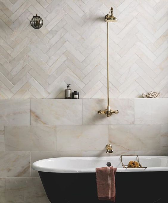 a bath tub sitting next to a shower head in a bathroom with white and black tile