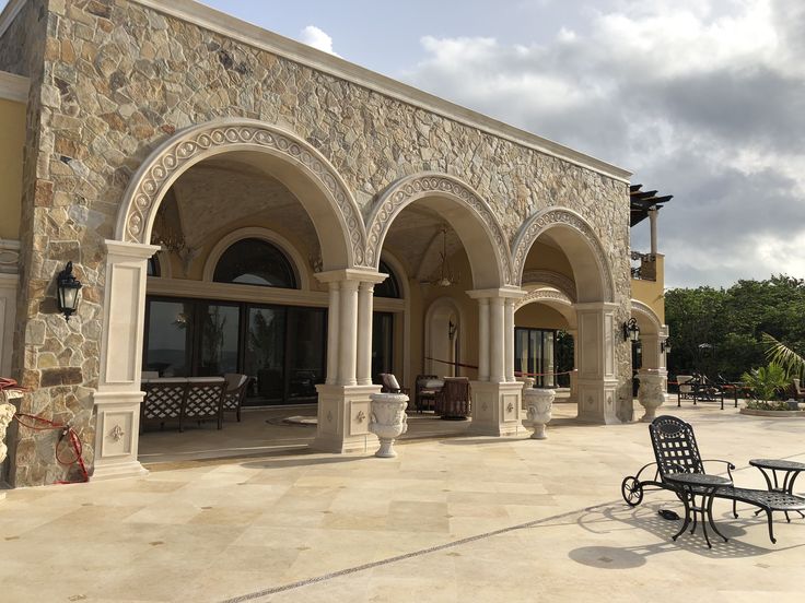 an outdoor patio with stone arches and chairs