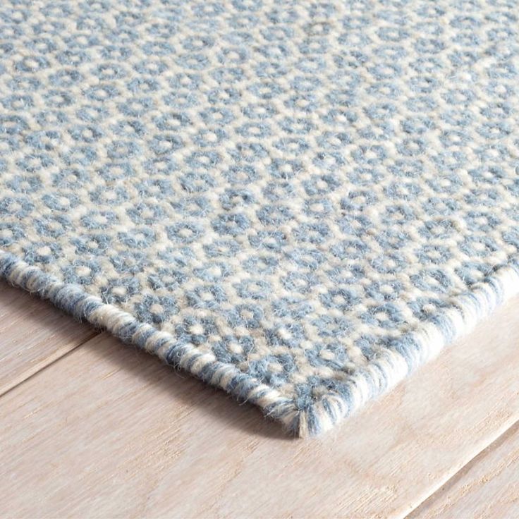 a blue and white rug on top of a wooden floor next to a wood floor