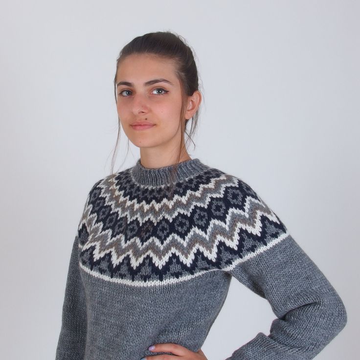 a woman wearing a sweater with an interesting pattern on the front and back, standing in front of a white background