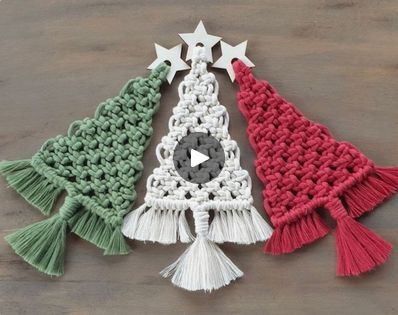 three crocheted christmas trees with tassels and stars on the top one