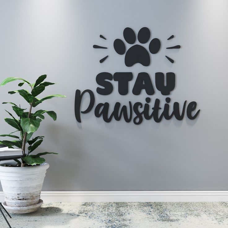 a sign that says stay pawsitive next to a potted plant