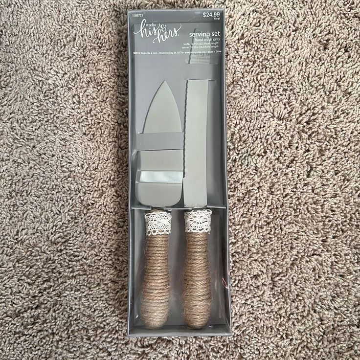 two silver and gold colored cake servers in a box on carpeted flooring