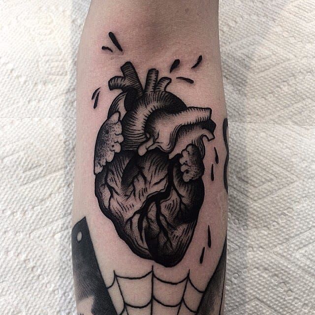 a black and white tattoo of a heart in a spider web on the right leg