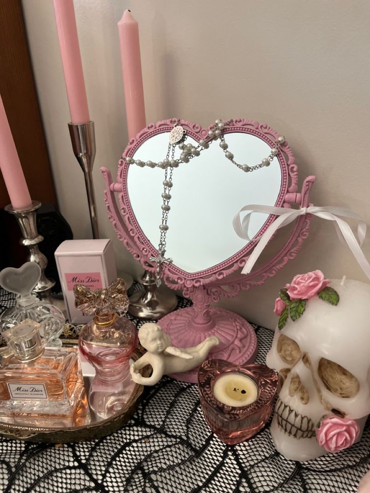 a table topped with candles and skulls next to a heart shaped mirror on top of a table