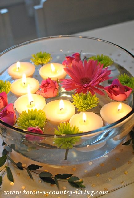 a glass bowl filled with flowers and lit candles