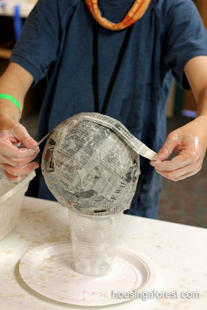 a person is making a paper mache globe