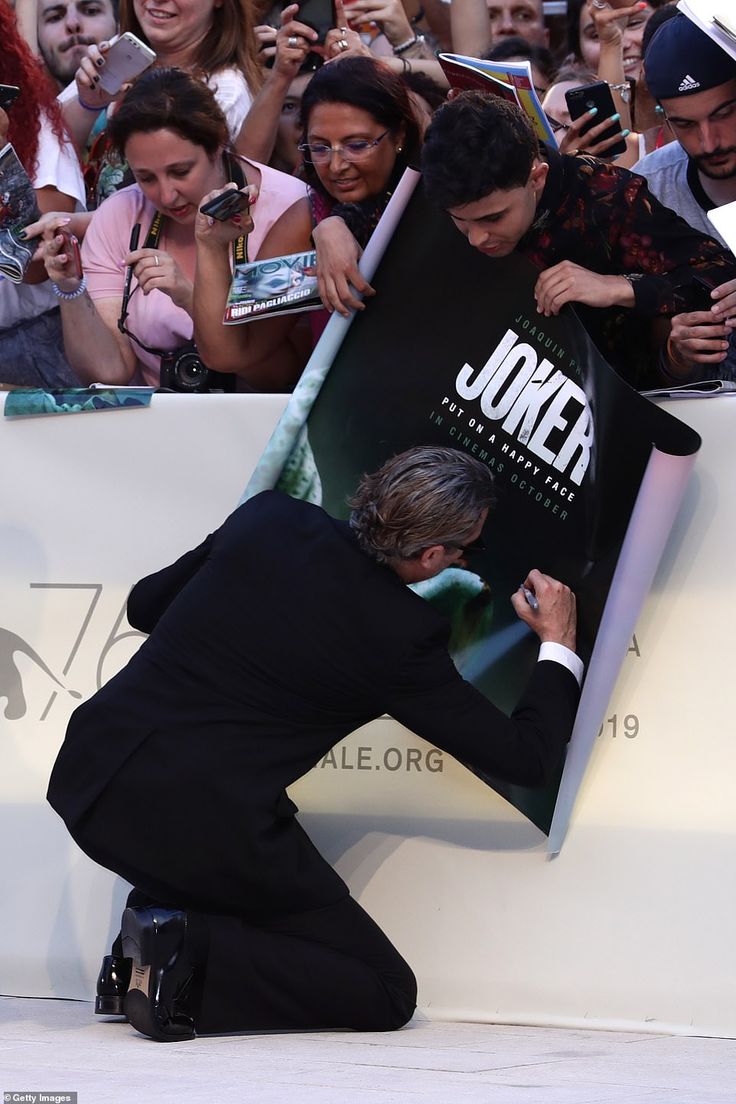 a man kneeling down in front of a sign with his hand on the back of him