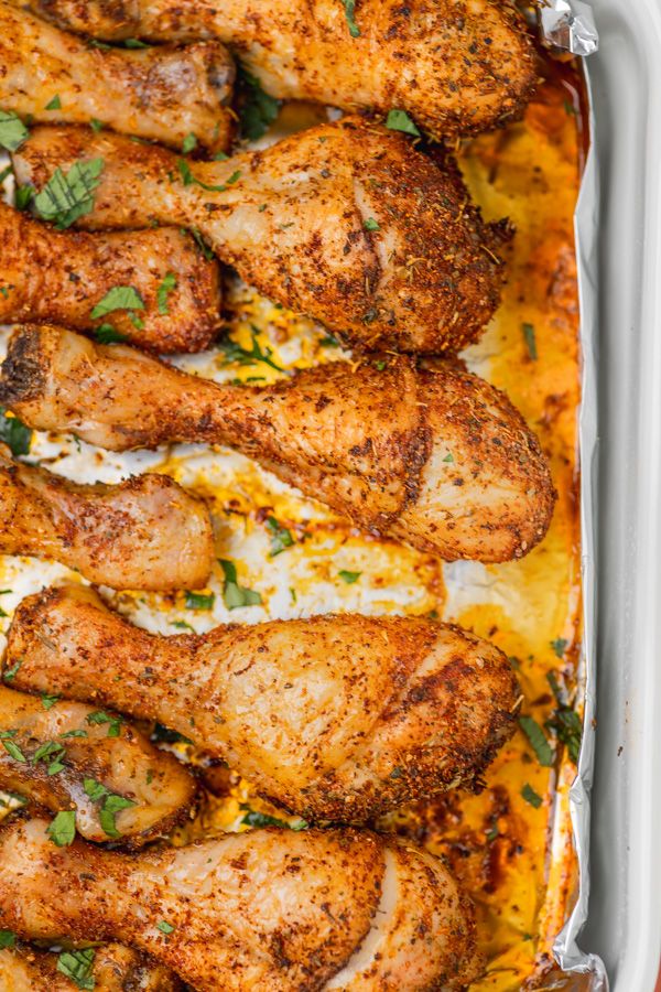 baked chicken legs in a casserole dish with parsley on top and melted cheese