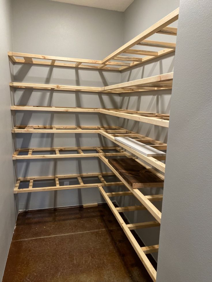 an empty room with shelves made out of wooden planks and plywood flooring