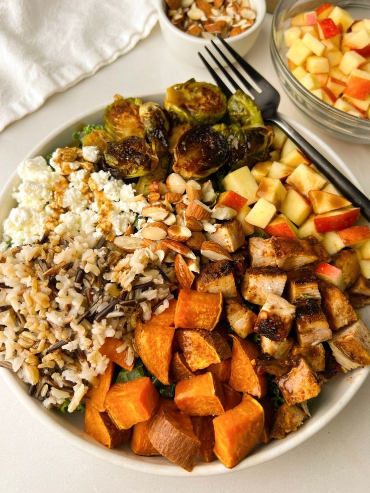 a white plate topped with rice and veggies next to bowls of food on a table