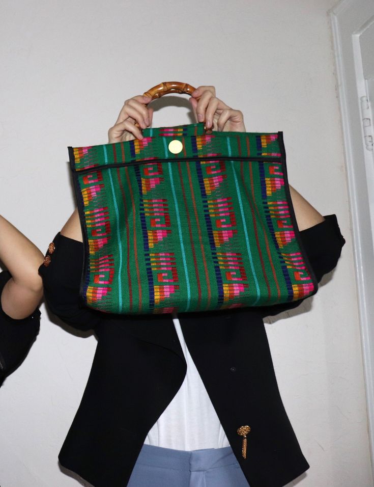 A unique roomy tote bag perfect for everyday use, the Nena bag is entirely made by hand in Spain. It is crafted in Cambaya fabric, a traditional Mexican cotton fabric made on wooden pedal looms, in Michoacán. This fun colorful bag is finished with a bamboo handle, and the interior is lined in black cotton fabric. Material: Cotton Cambaya fabric, bamboo handle HANDMADE IN SANTANDER, SPAIN Size: 16 x 15 x 5 in / 40,5 x 38 x 13 cms The Nena bag comes in a Cuckoo B cotton dust bag. Cuckoo B believes Black Cotton Fabric, Colorful Bags, Traditional Mexican, Bag Green, Bamboo Handles, Mexican Style, Green Bag, Black Cotton, Mango