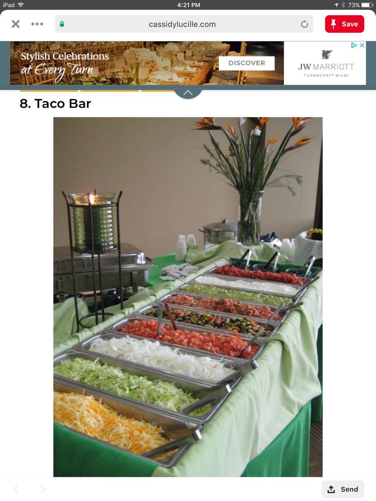 a table with many trays of food sitting on it's sides and flowers in the middle