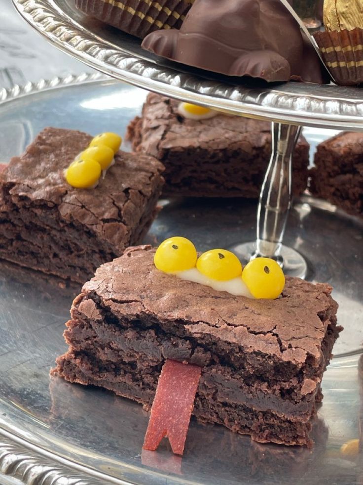 some brownies with yellow candies are on a silver platter