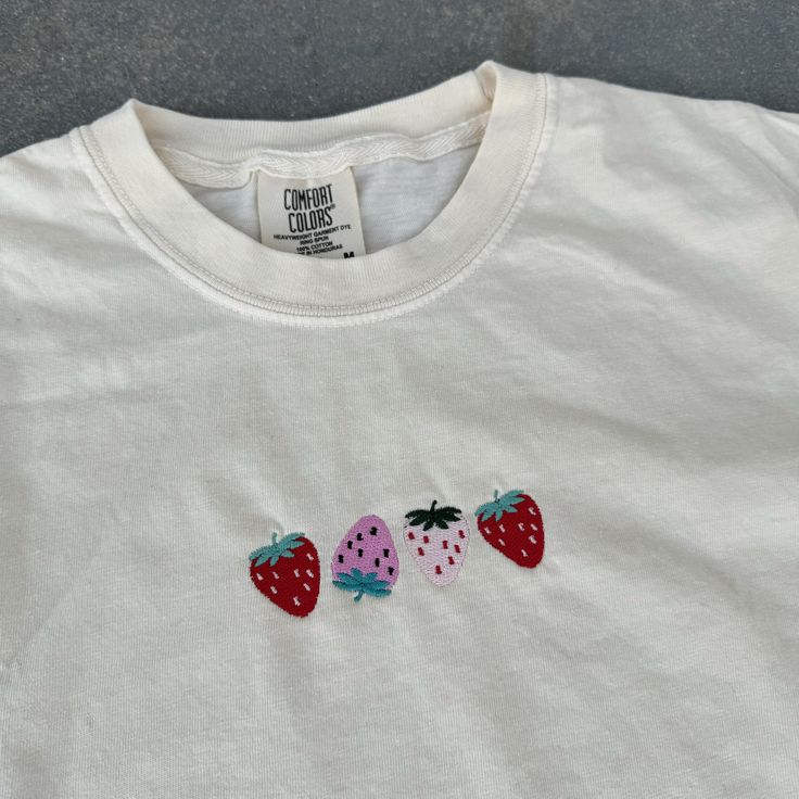 three embroidered strawberries on a white t - shirt