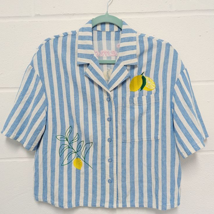 Cropped oversized linen shirt, great for those hot and sunny summer days. Pale blue and white soft linen and viscose shirt with embroidered lemons on the front and back. Text on the reverse reads 'Lemon Squeezy' in pink embroidered lettering. These are good quality hardly warn second hand shirt which I have embroidered and refashioned. They are oversized in style and there are 3 available in different sizes.  Please check your size below: Original garment size - Woman's UK 8 Material - 55% Linen 45% Viscose Measurements - Armpit to armpit (laying flat): 51cm Length (collar to hem): 54cm Sleeve: Short 22cm from shoulder seam Original garment size - Woman's UK 10 Material - 55% Linen 45% Viscose Measurements - Armpit to armpit (laying flat): 53cm Length (collar to hem): 54cm Sleeve: Short 22 Summer Embroidered Relaxed Fit Shirt, Summer Embroidered Collared Tops, Embroidered Relaxed Fit Shirt For Summer, Collared Tops With Floral Embroidery For Vacation, Vacation Embroidered Collared Shirt, Embroidered Collared Shirt For Vacation, Floral Embroidered Collared Shirt For Vacation, Embroidered Vacation Shirt With Collar, Summer Floral Embroidered Relaxed Fit Shirt