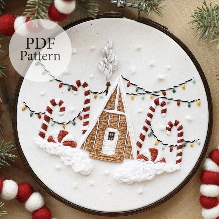 a cross stitch christmas ornament with candy canes and a gingerbread house