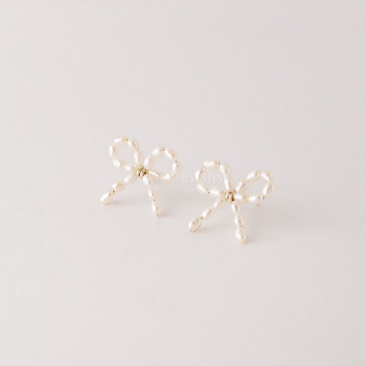 Expertly crafted with sterling silver and freshwater pearls, these Pearl Bow Earrings add a touch of elegance and sophistication to any outfit. Perfect for bridesmaids or as a gift for her, they make a statement with their delicate bow design. Elevate your style with these timeless and classic pearl earrings.• Sold in pairs• Material: High Quality Sterling Silver• Finish: Sterling Silver ∙ 18k Gold ∙ 18k Rose Gold• Featuring 2cm x 2cm bow with a high quality white freshwater pearls Feminine White Jewelry With Bow, Elegant Wedding Jewelry With Decorative Bow, Feminine Pearl White Pearl Earrings For Party, White Bow Jewelry For Formal Occasions, White Formal Jewelry With Bow Detail, Formal White Jewelry With Decorative Bow, Formal White Jewelry With Bow Detail, Formal White Bow Jewelry, White Pearl Earrings With Bow For Wedding