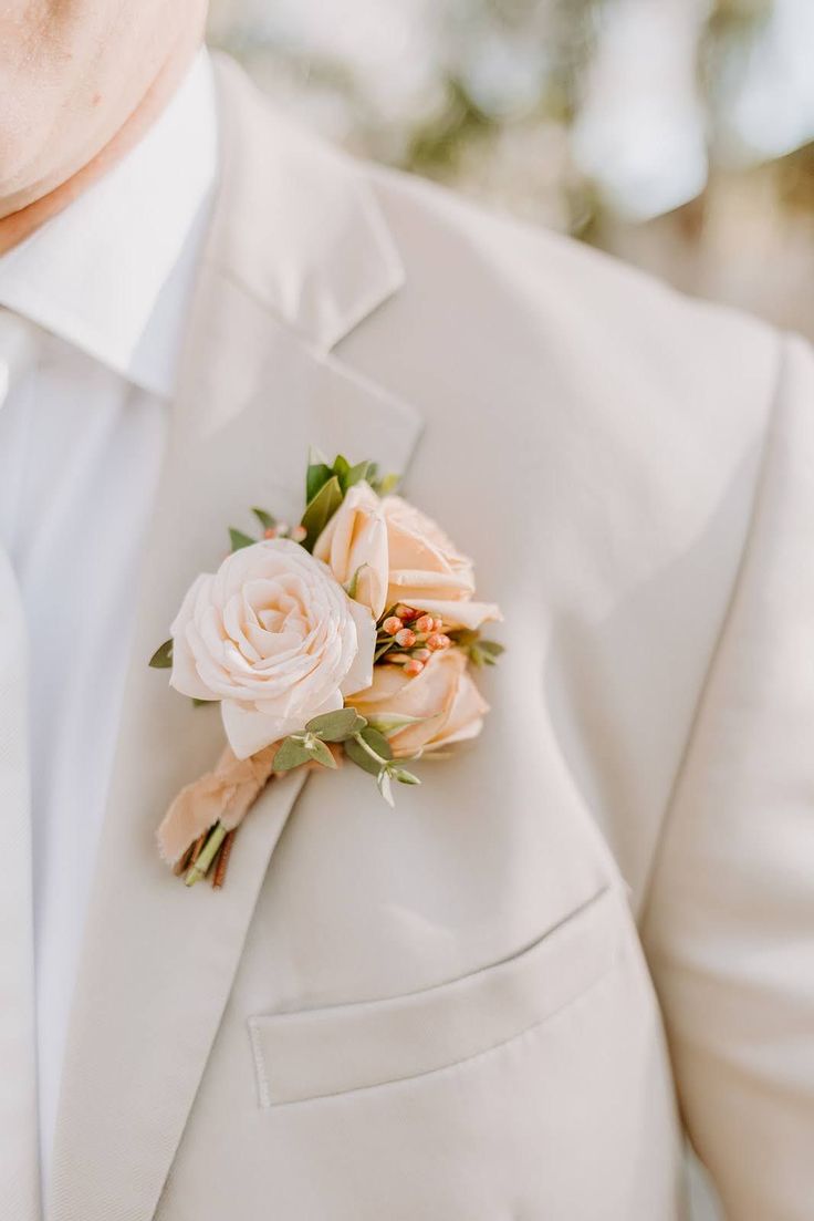 a man in a white suit with a boutonniere on his lapel