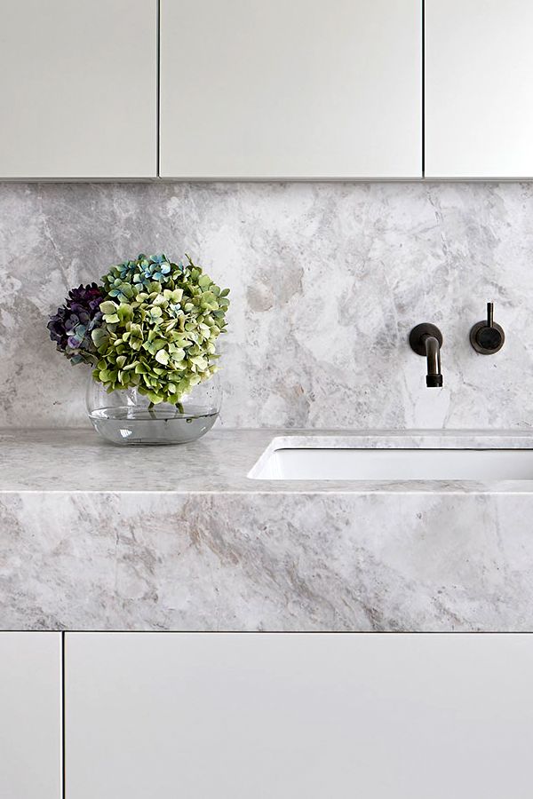 a white marble kitchen counter top with two sinks and a faucet in the middle