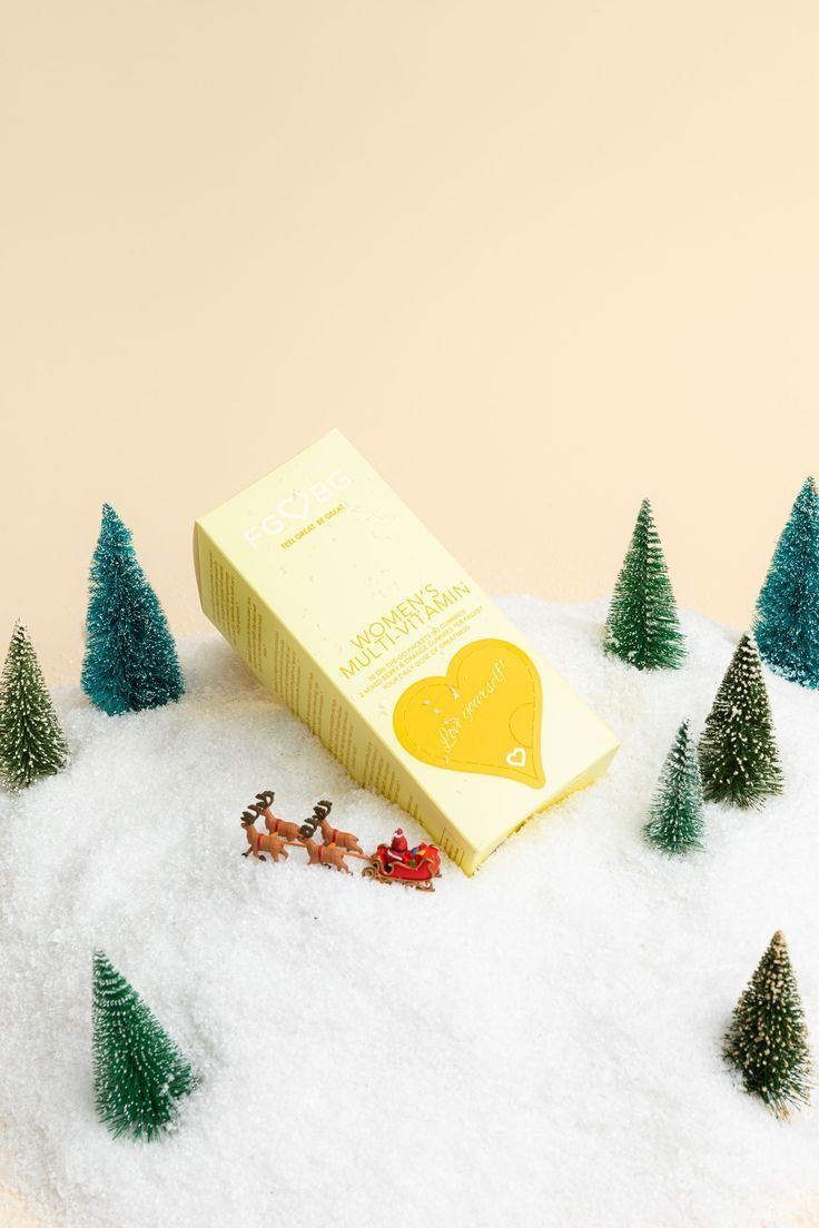 a box of chocolate sitting on top of snow covered ground next to small christmas trees