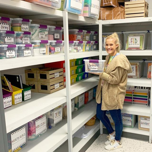 a woman standing in front of shelves filled with boxes and folders, smiling at the camera