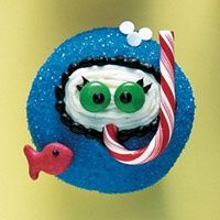 a blue cupcake with white frosting and green eyes