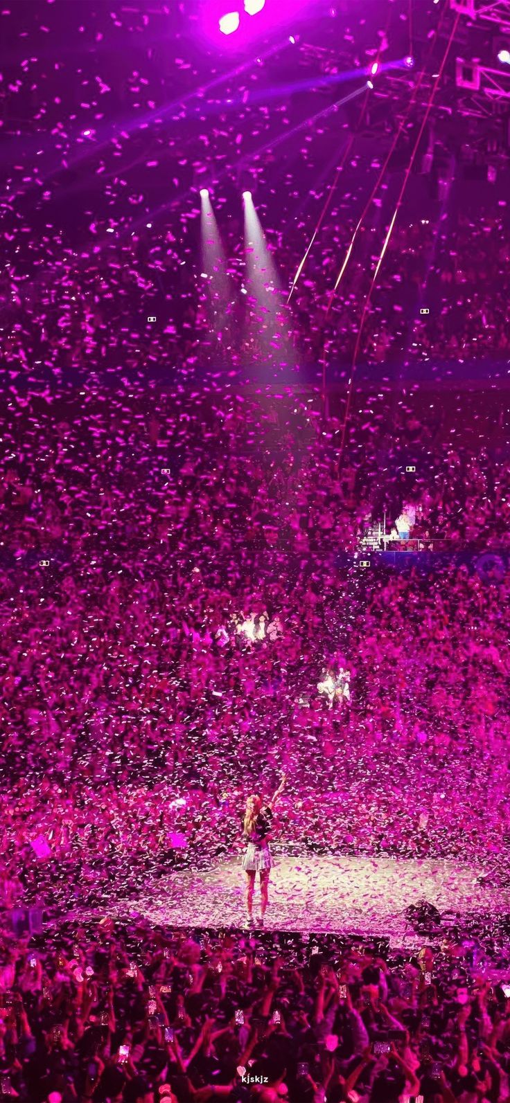 confetti is thrown in the air at a concert with purple lighting and fans