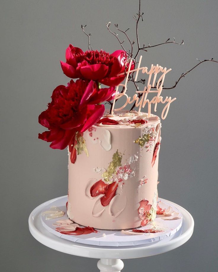 a pink birthday cake with red flowers on top and the words happy birthday written on it