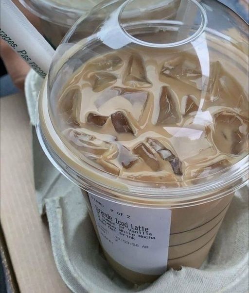 an iced coffee in a plastic cup with ice cubes on the top and lid